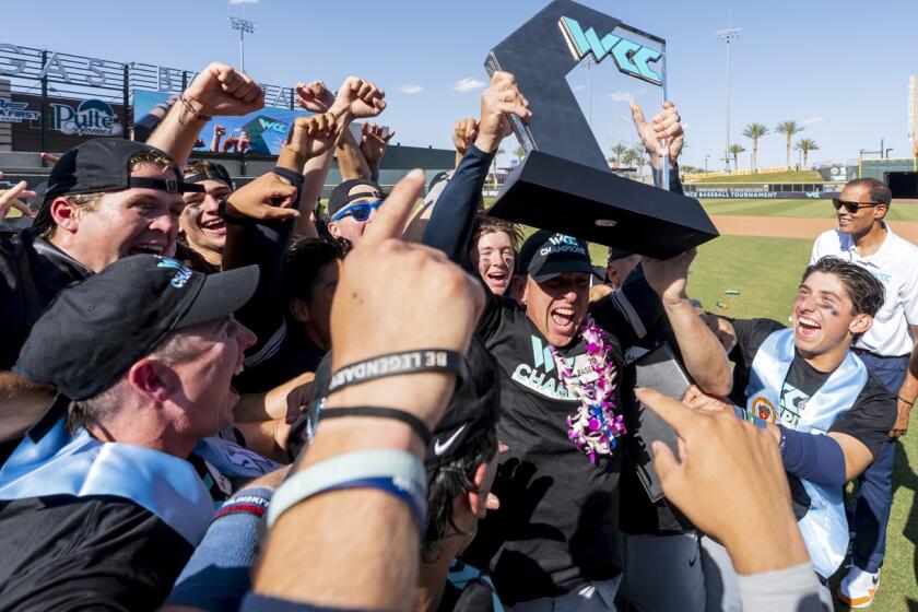 USD baseball coach Brock Ungricht holds up 2024 WCC Tournament championship trophy as Toreros players celebrate around him.