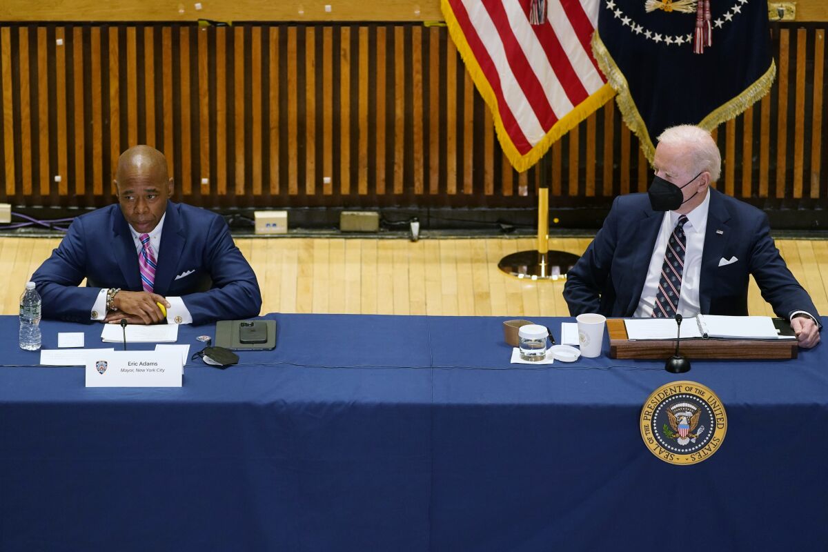 President Biden listens to New York Mayor Eric Adams speak at a table indoors