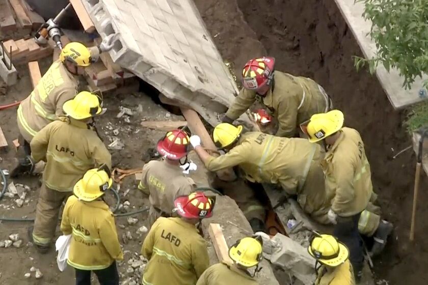 Los Angeles Fire Department crews work to rescue a person trapped under a wall that fell at a construction site in the 10500 block of North Glenoaks Boulevard in Pacoima. One injured person has already been taken to a hospital with back pains, but crews are working to rescue a second.