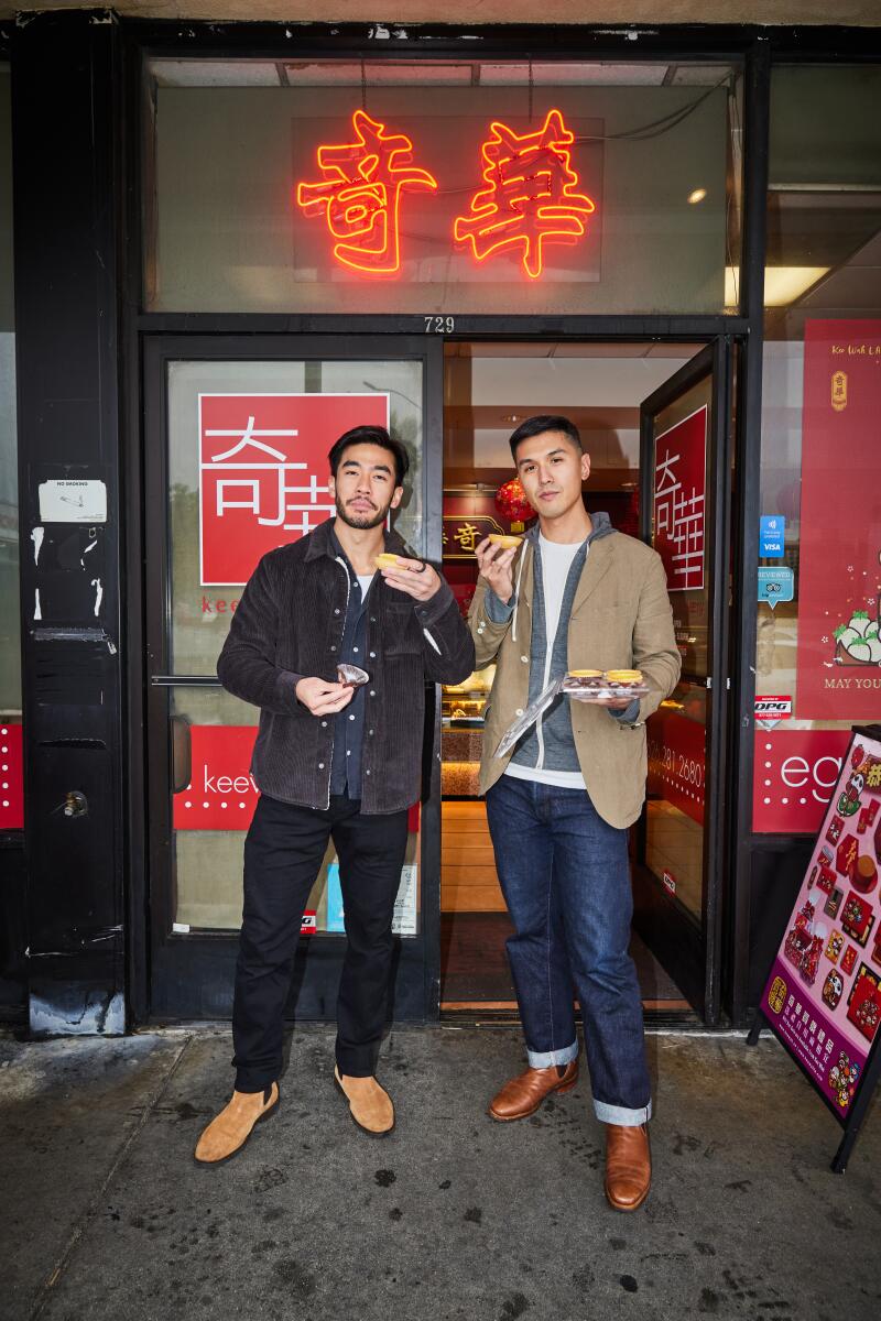 Justin Chien and Byron Wu outside of glass doors under neon Chinese characters.