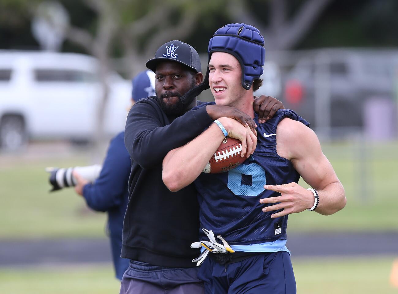 Reciever John Humphreys, right, and coach Karif Byrd have a laugh after big catch during a spring football showcase practice at Corona del Mar High on Wednesday.