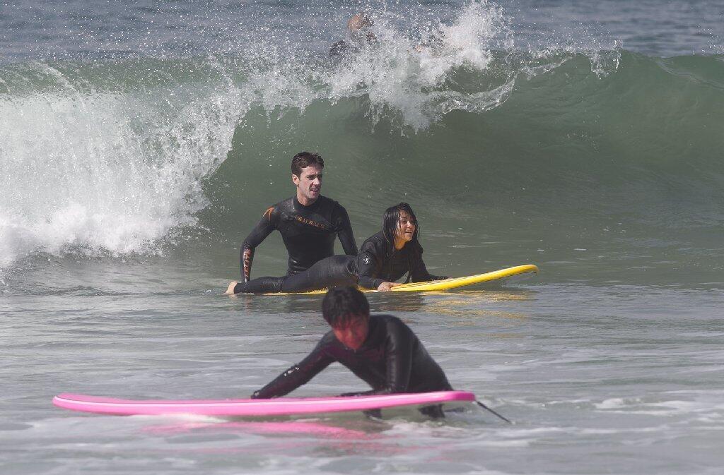 Volcom surf instructor Brett Myers, top left, prepares to push off a participant of the Save Our Youth’s Surf Days program in west Newport on Thursday.