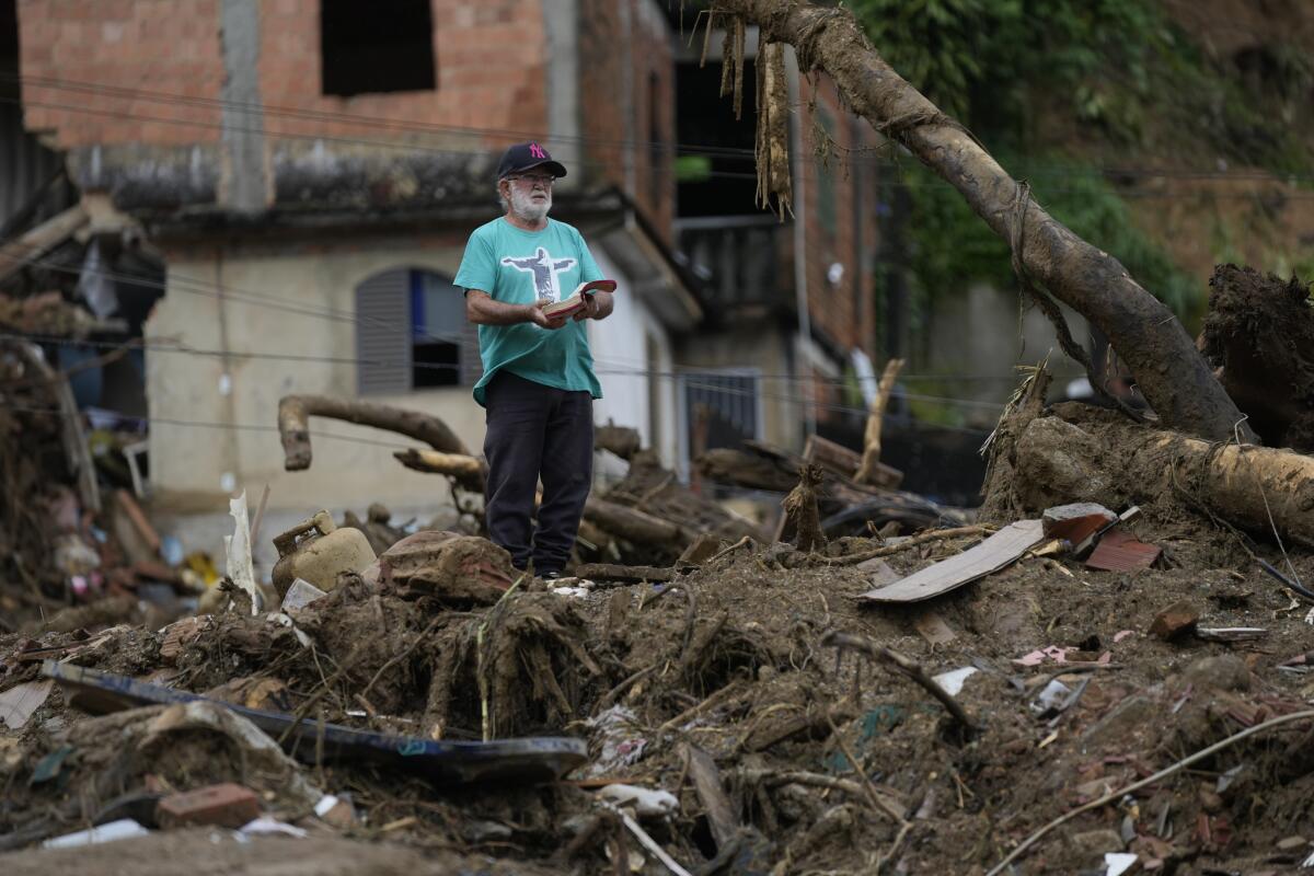 A man with a Bible stands amid the debris of homes destroyed by mudslides