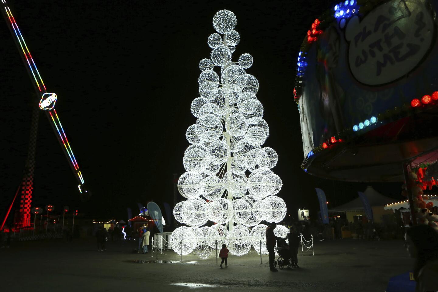 A child, walks in front of an illuminate Christmas tree at the Christmas Luna park in capital Nicosia, Cyprus, Sunday, Dec. 15, 2019. Seasonal entertainments are happening at many locations over the island with special events planned for Christmas and for New Year. (AP Photo/Petros Karadjias)