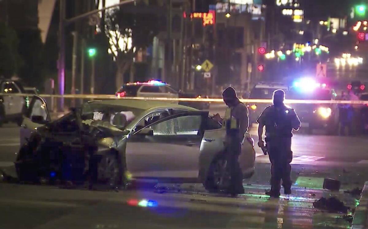 Investigators examine a wrecked car at night.