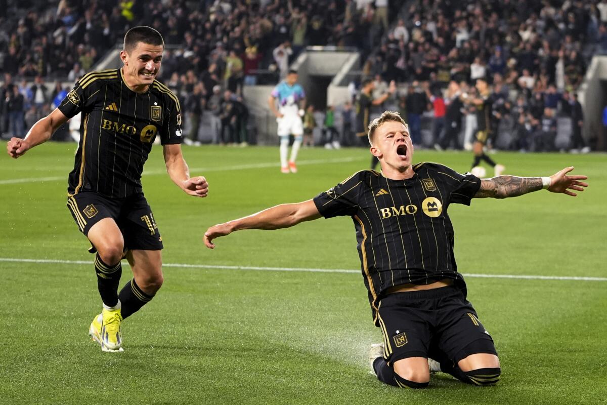 Mateusz Bogusz kneels and screams as Sergi Palencia runs up smiling.