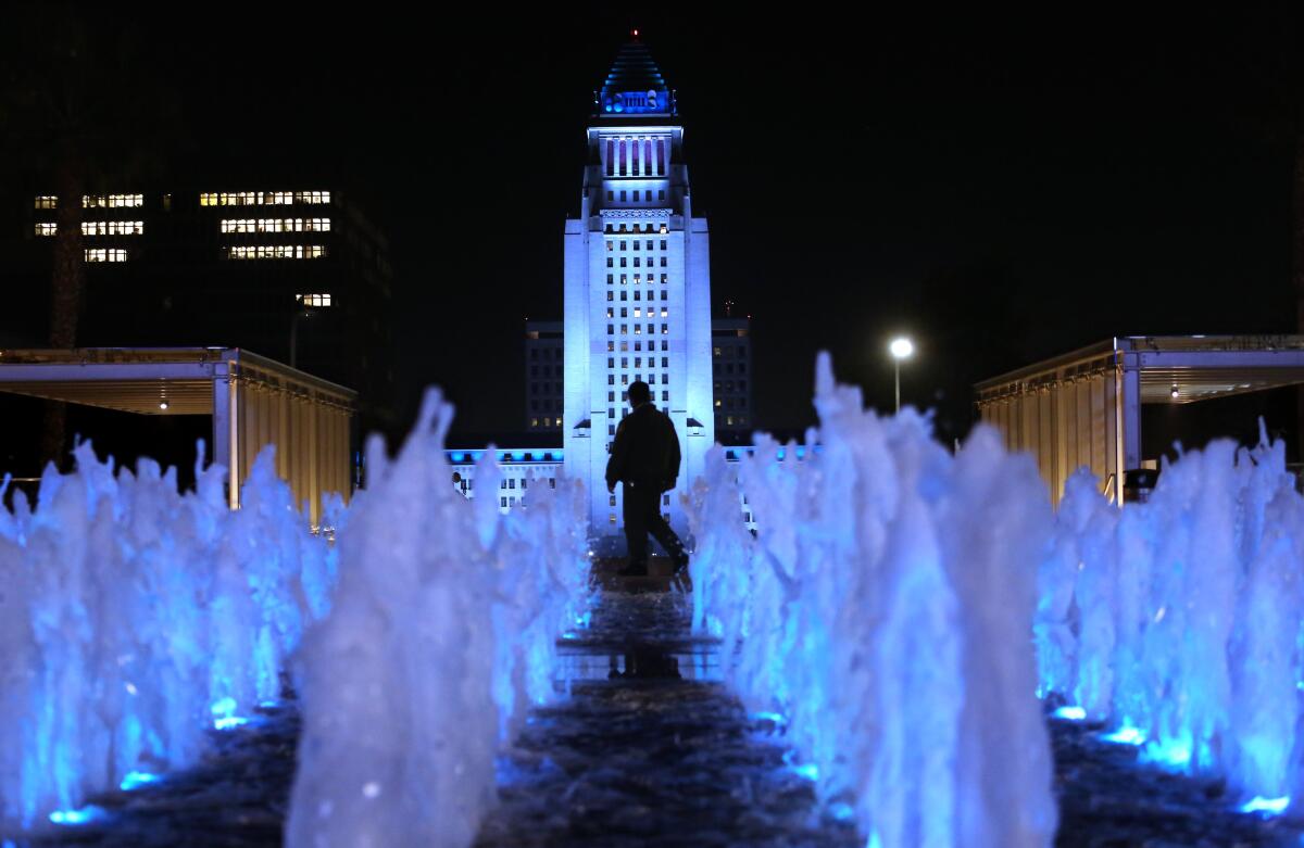 A security officer is framed by Los Angeles City Hall lighted in Dodger blue through the weekend.