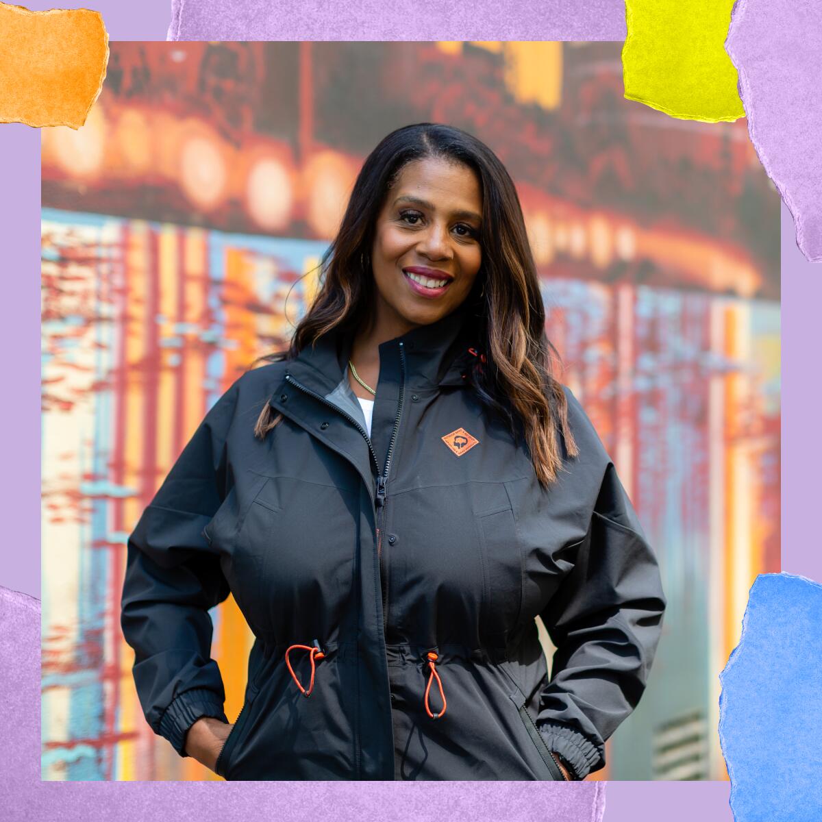 A woman in a zip-up jacket smiles for a photo.