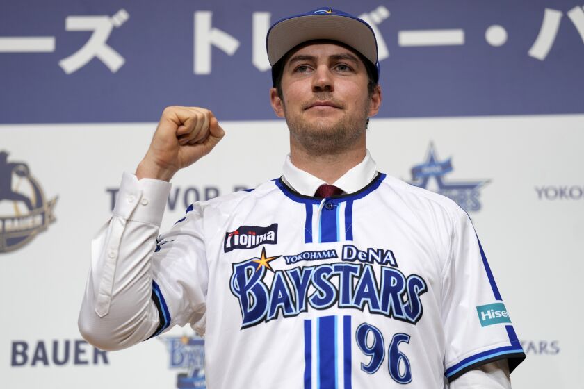 Trevor Bauer with his new uniform and cap of Yokohama DeNA BayStars poses for photographers during a photo session of the news conference Friday, March 24, 2023, in Yokohama, near Tokyo. (AP Photo/Eugene Hoshiko)