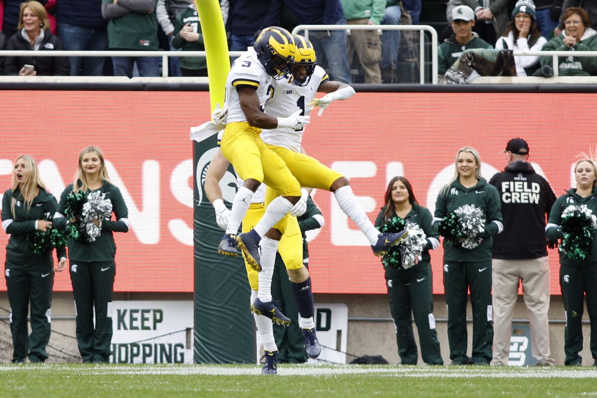 Michigan's Andrel Anthony, right, and A.J. Henning (3) celebrate Anthony's touchdown reception during the first quarter of an NCAA college football game against Michigan State, Saturday, Oct. 30, 2021, in East Lansing, Mich. (AP Photo/Al Goldis)