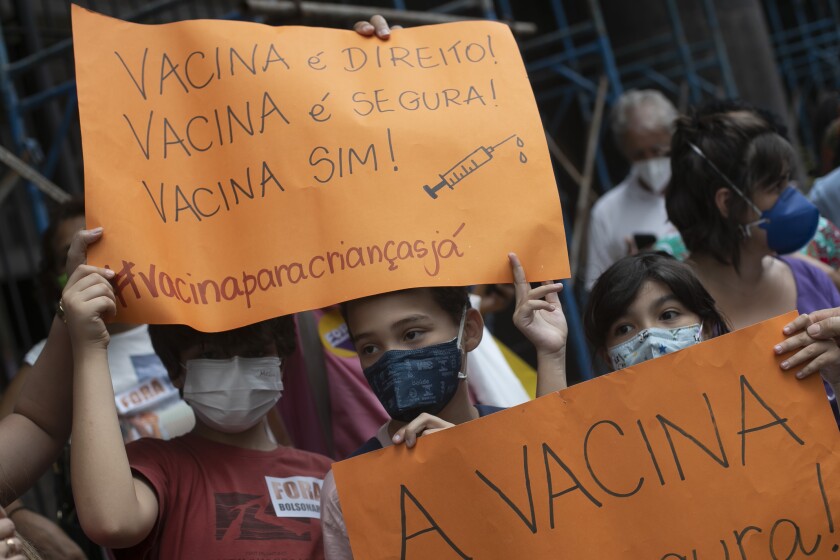 Children hold the Portuguese messages: "Vaccine is a right! Vaccine is safe! Vaccine yes!' during a demonstration in favor of COVID-19 vaccinations for children outside Rio state's Ministry of Health office in Rio de Janeiro, Brazil, Wednesday, Jan. 5, 2022. (AP Photo/Bruna Prado)
