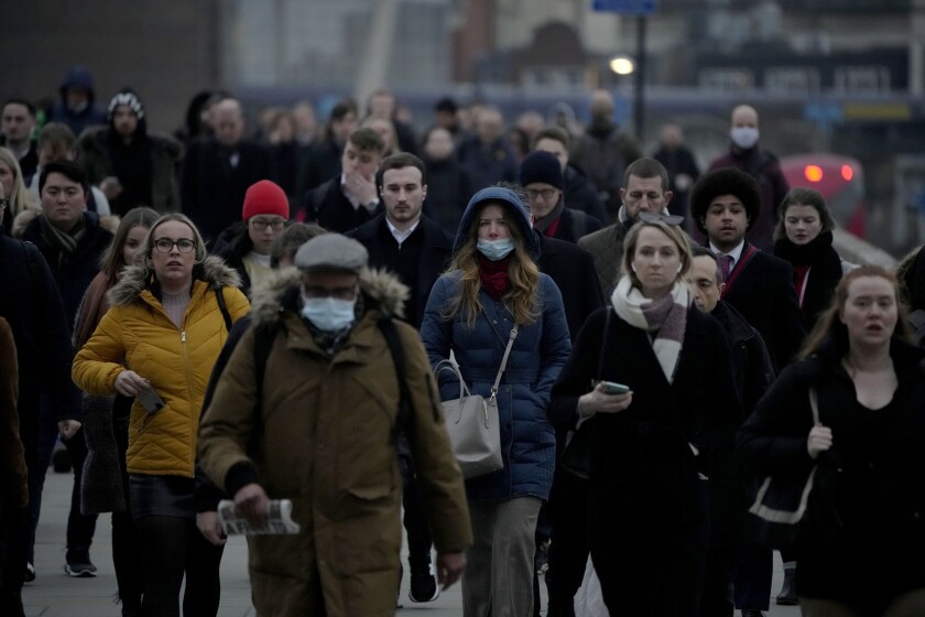 FILE - Workers walk over London Bridge towards the City of London financial district during the morning rush hour, in London, Monday, Jan. 24, 2022. For many in the U.K., the pandemic may as well be over. Mask requirements have been dropped everywhere and free mass testing is a thing of the past. The sense of freedom is widespread even as infections soared to record levels in Britain in March, driven by the milder but more transmissible Omicron BA.2 variant that’s rapidly spreading around Europe, the U.S. and elsewhere. (AP Photo/Matt Dunham, File)