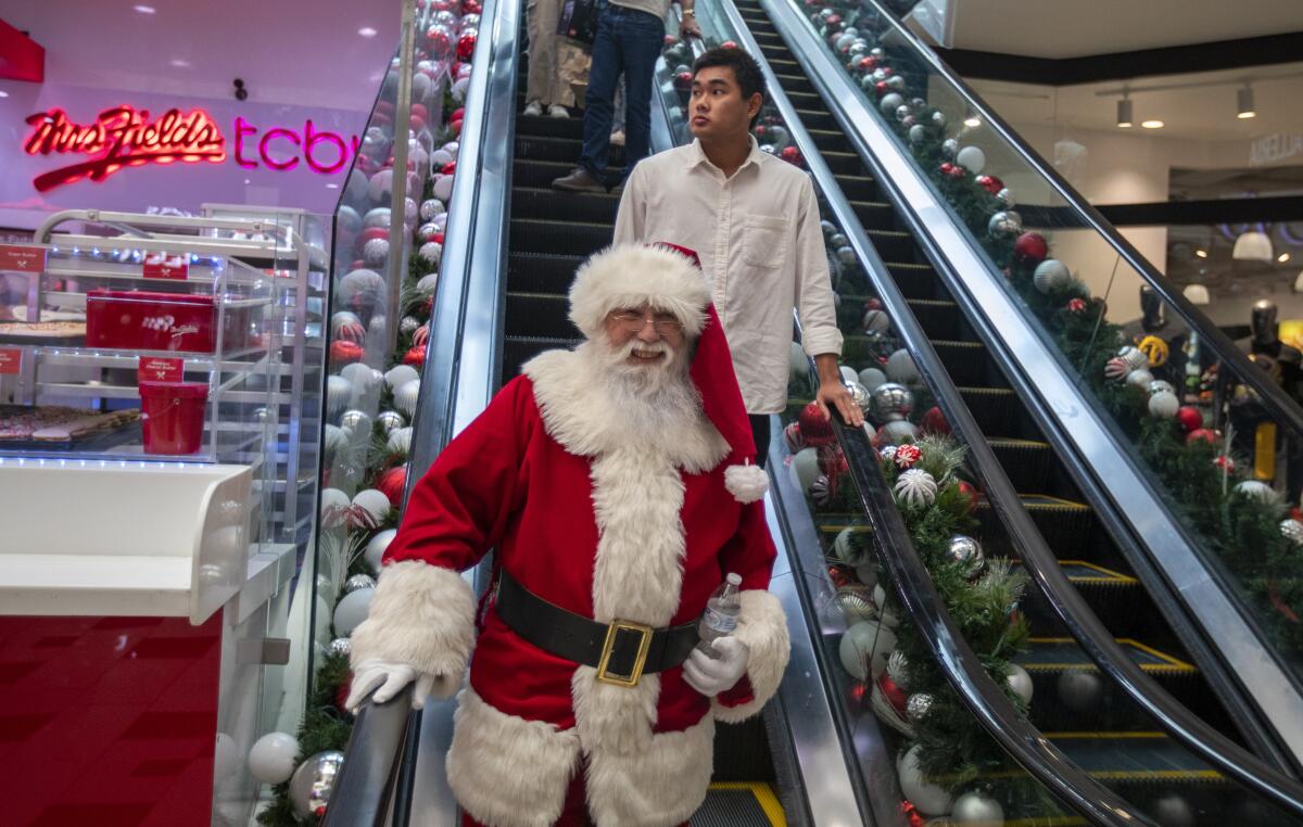 Santa takes the escalator to work on Black Friday at the Glendale Galleria.