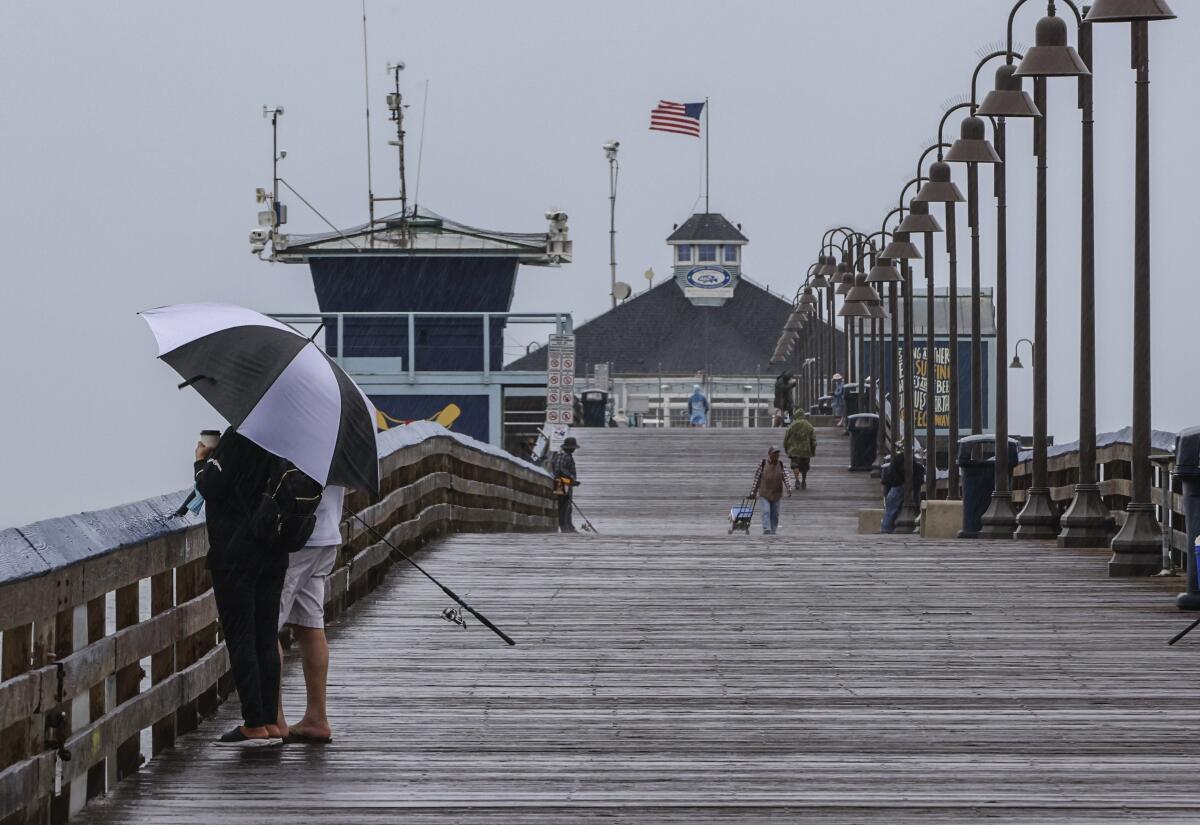 People at the Imperial Beach Pier take in the stormy weather.
