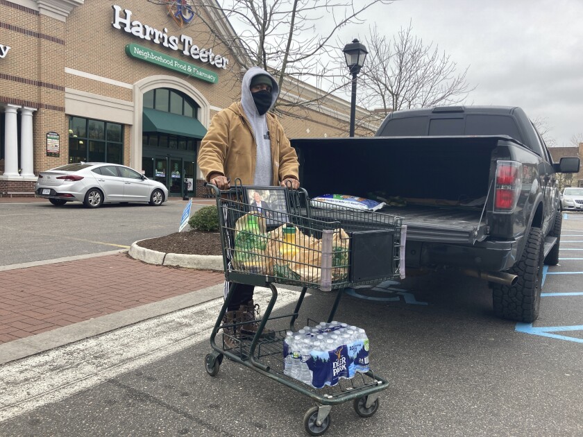 Chris Stokes picks up extra provisions at a grocery store in Norfolk, Va., on Friday Jan. 21, 2022, as the city prepares for an upcoming snowstorm. (AP Photo/Ben Finley)