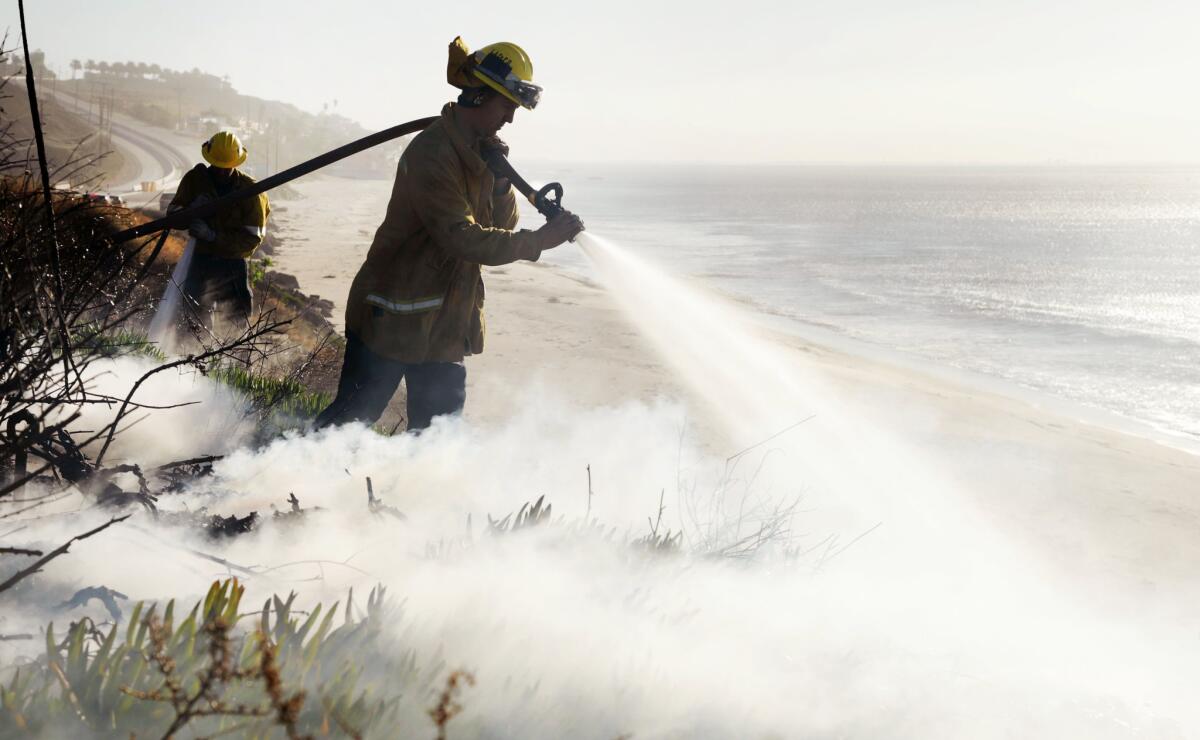 Firefighters from the LA County Fire Department put out a flare up along the PCH across the street from the Malibu RV Park.