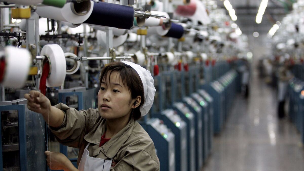 A worker operates a machine to make socks at a production plant in Yiwu, China. (Eugene Hoshiko / Associated Press)