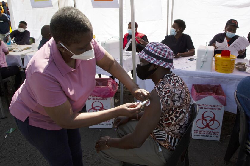 A patient receives a Johnson & Johnson vaccine at a pop-up vaccination centre, at the Bare taxi rank in Soweto, South Africa, Friday, Aug. 20, 2021. Faced with slowing numbers of people getting COVID-19 jabs, South Africa has opened eligibility to all adults to step up the volume of inoculations as it battles a surge in the disease driven by the delta variant. (AP Photo/Denis Farrell)