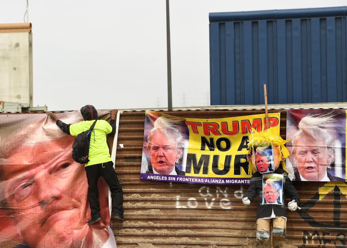 A Trump protester hangs a banner on the Mexico side of the border.