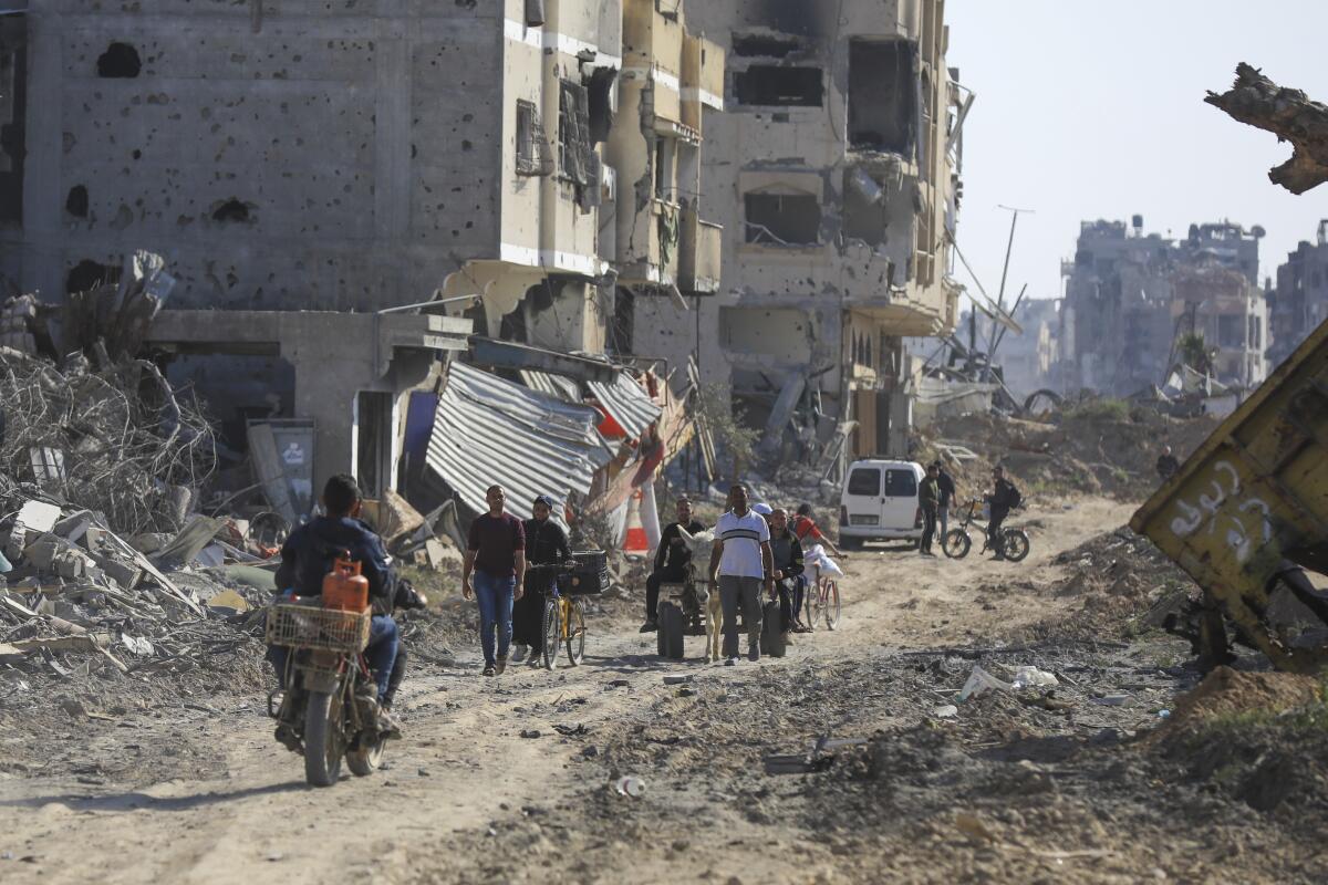 Palestinians walk through the destruction left by the Israeli air and ground offensive in Khan Yunis, southern Gaza Strip.