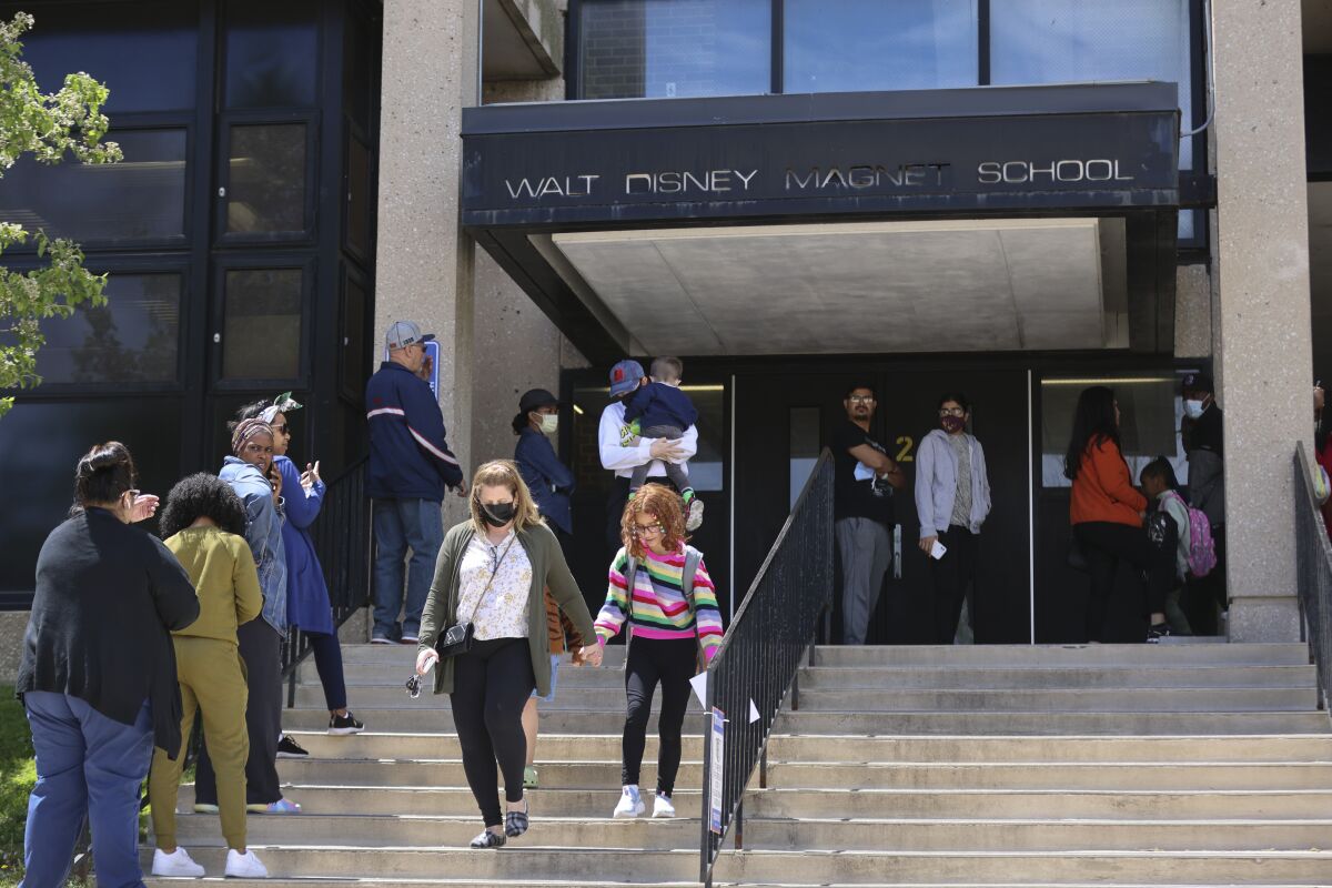 Parents wait in line to pick up their children at Walt Disney Magnet School, Tuesday May 17, 2022 in Chicago. A Chicago mother has been charged with child endangerment after a gun in her second grader's backpack accidentally discharged at the school, injuring a 7-year-old classmate, police said Wednesday. According to police, the backpack was in the boy's classroom when, just before 10 a.m. on Tuesday, the gun discharged. (Anthony Vazquez /Chicago Sun-Times via AP)