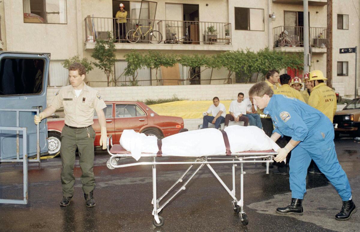 L.A. county coroner worker wheels a body on a gurney