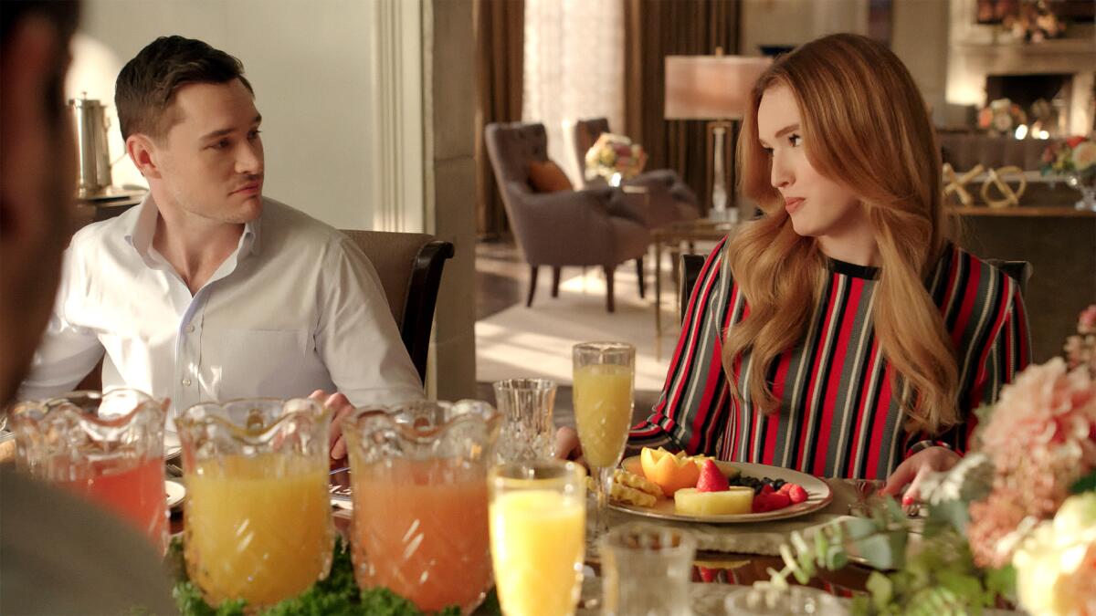  A man and a woman look at each other while sitting at a dining table.