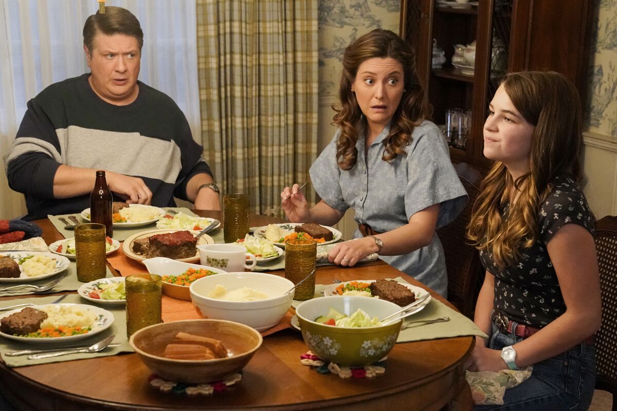 Lance Barber, Zoe Perry and Raegan Revord have a conversation at the dining table in a scene from "Young Sheldon"