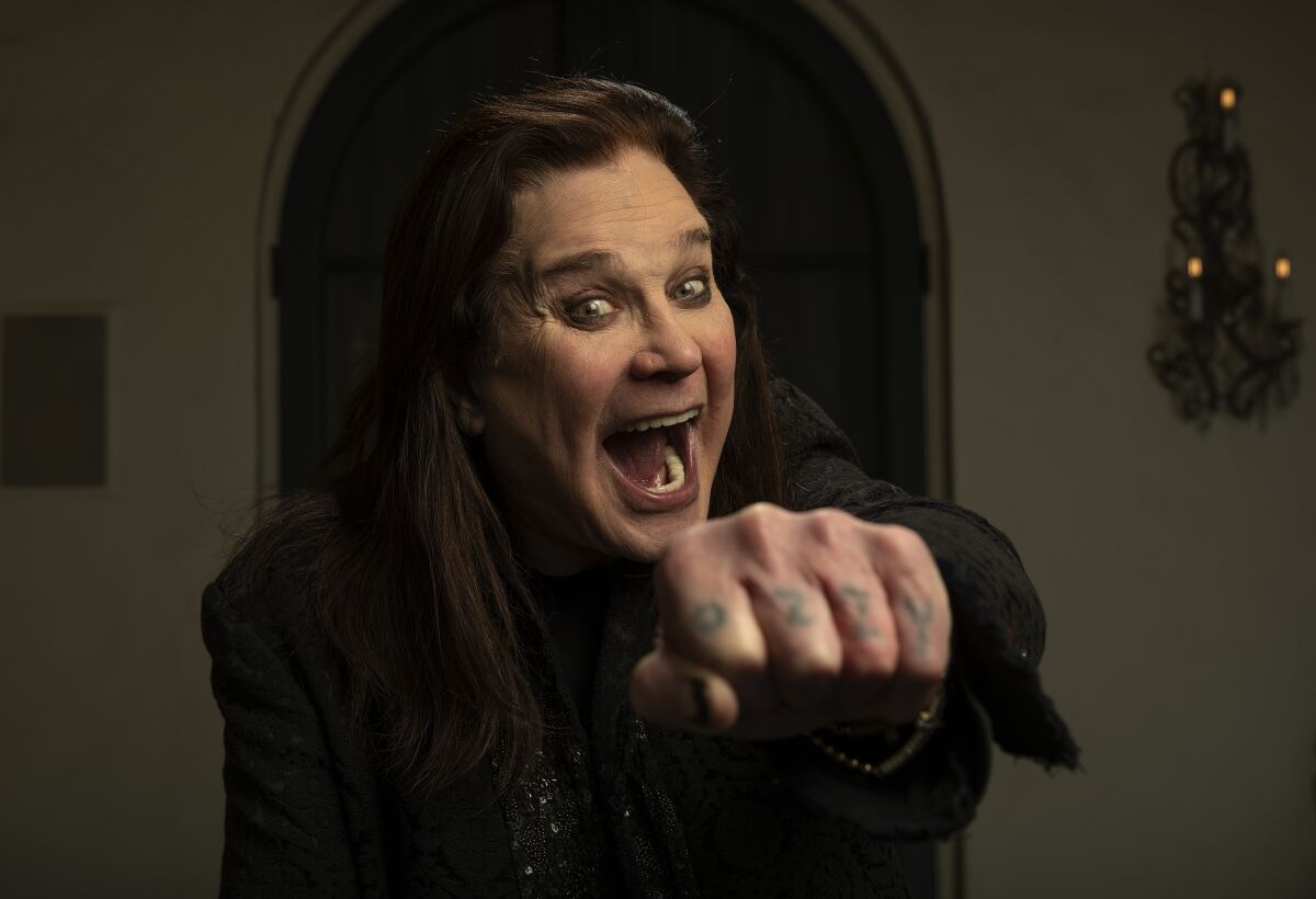 A man with dark hair opens his mouth and points his left fist forward