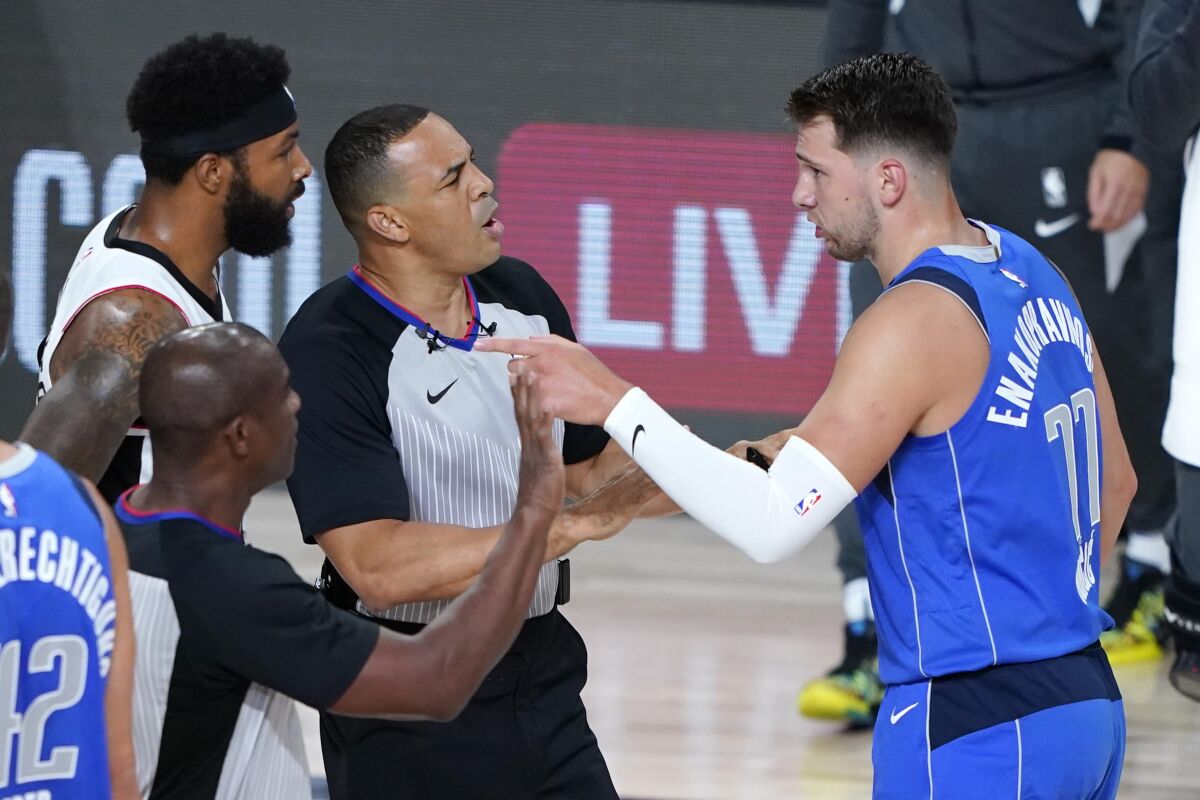 Officials get between Dallas Mavericks guard Luka Doncic, right, and Clippers forward Marcus Morris Sr.