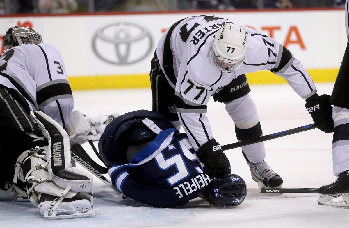 Kings center Jeff Carter (77) shoves Jets center Mark Scheifele to the ice in front of goaltender Jonathan Quick (32) in the second period Sunday in Winnipeg.