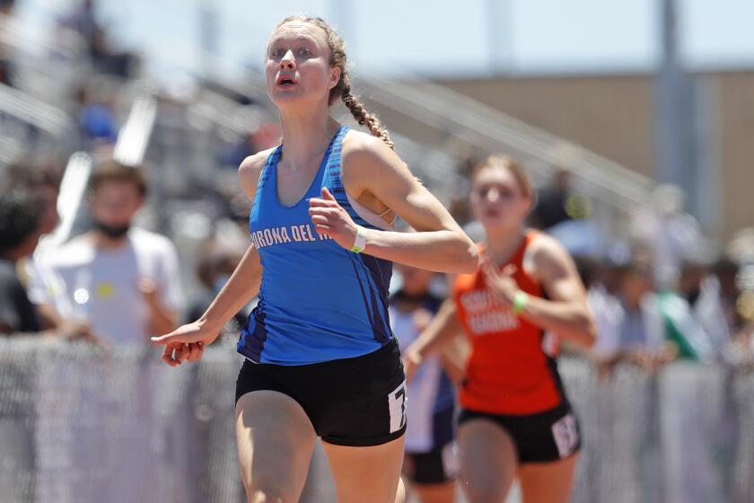 Caroline Glessing of Corona Del Mar, in blue, crosses the finish in first place in the girls' 200 meters in the CIF Southern Section Division 3 track and field championships at Estancia High School in Saturday.