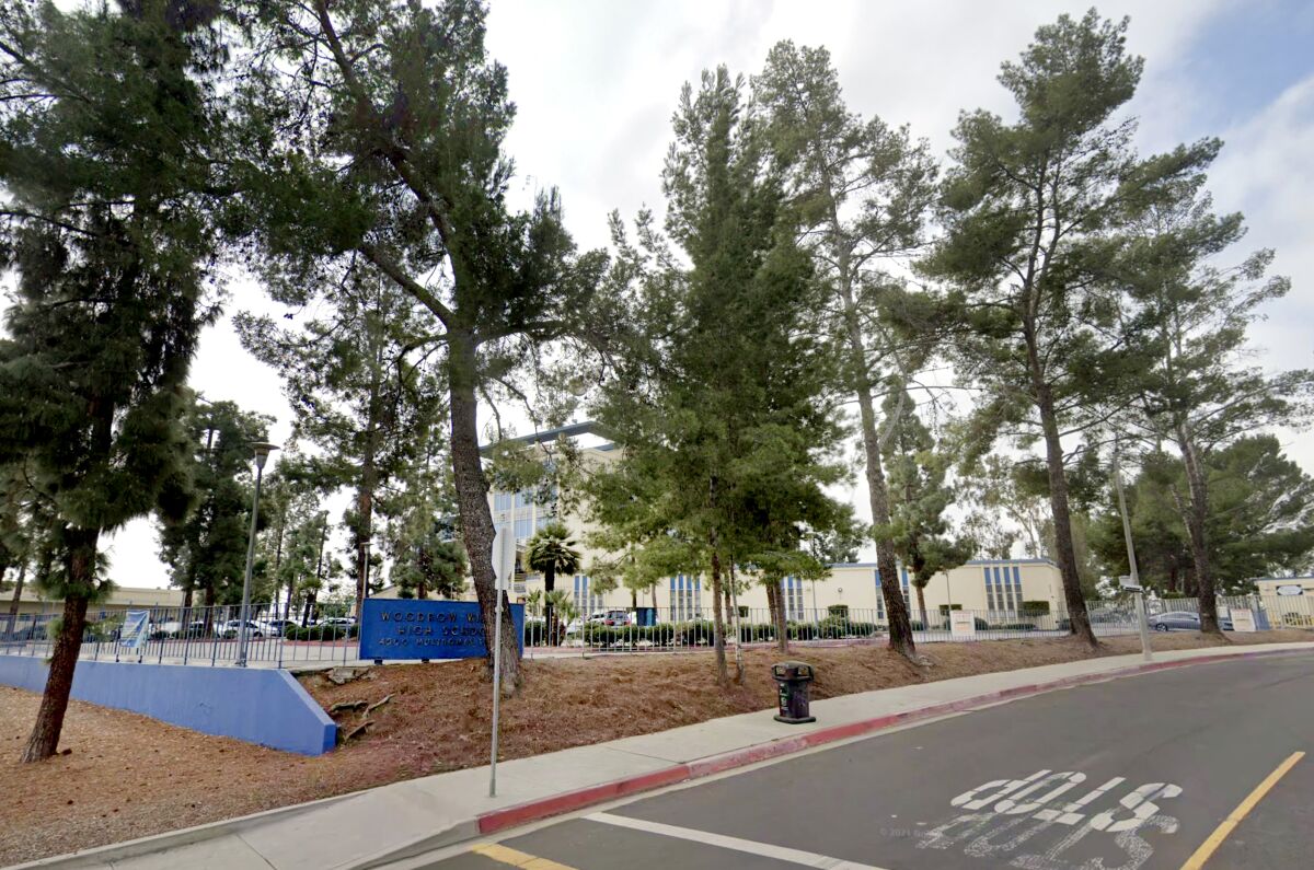 A view of trees and buildings on school campus next to a road