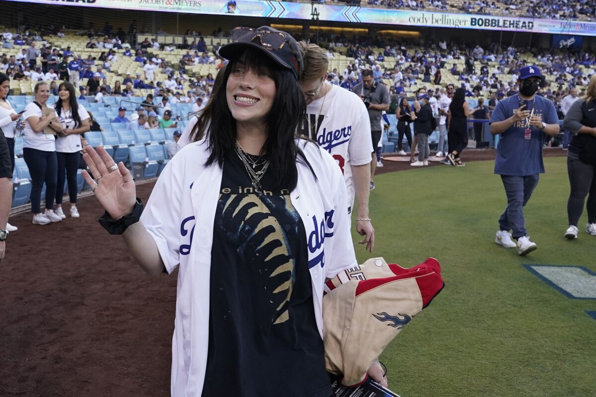 Woman wearing a hat and a Dodgers jersey  walks on a baseball field. 