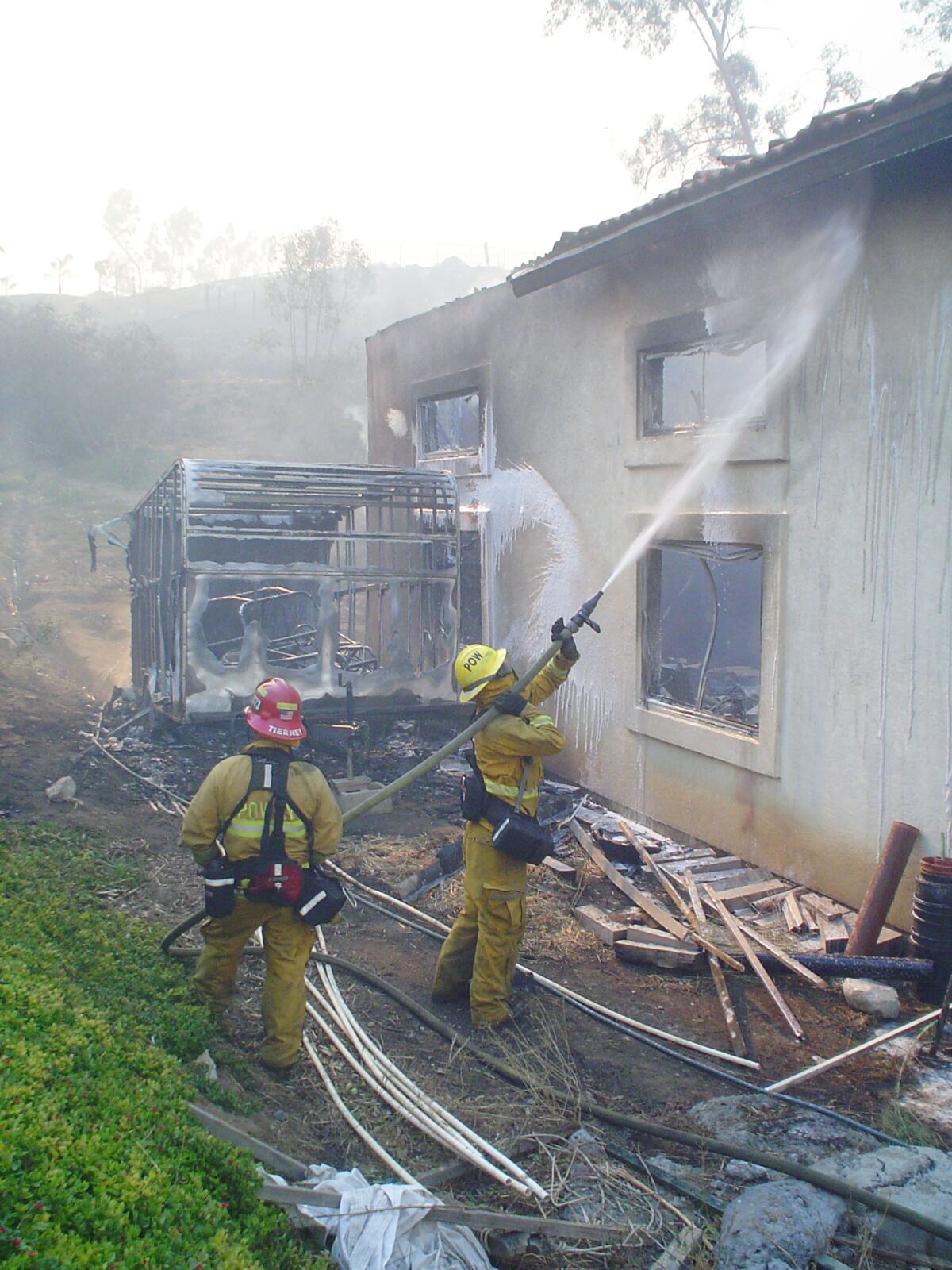 Poway firefighters extinguishing flames at a home during the Witch Creek fire in 2007.