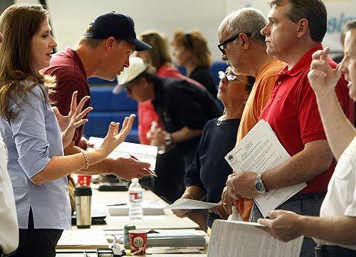 Representatives from the city of Yorba Linda, left, talk to victims of the Freeway Complex fire at the local assistance center in the East Anaheim Gym.