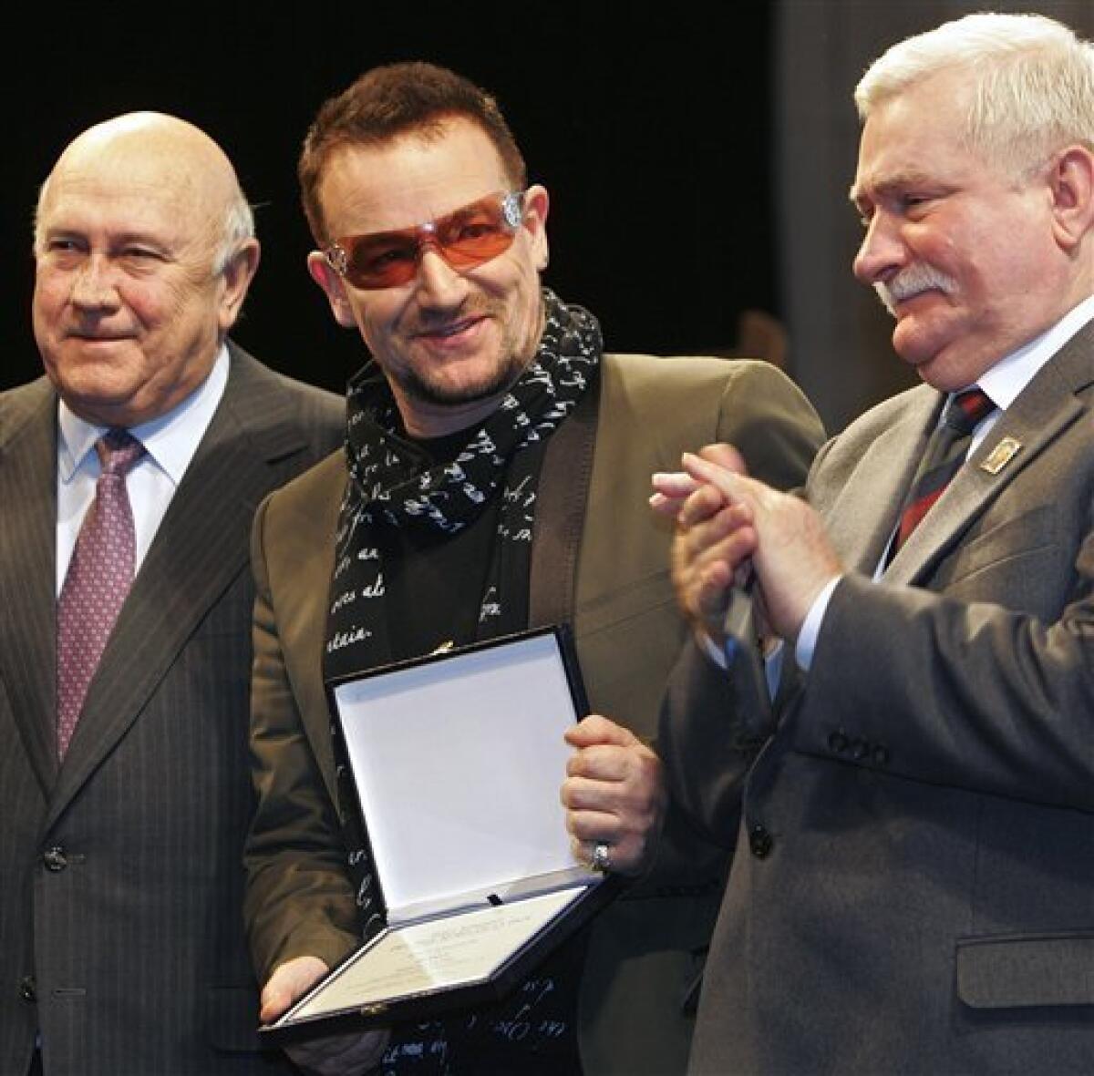 FILE - This is a Friday, Dec. 12, 2008 file photo of Irish singer and activist Bono, center, as neposes with 1993 Nobel Peace Laureate F. W. de Klerk, left, and 1983 Nobel Peace Laureate Lech Walesa after Bono was awarded with the Peace Summit Award during the 9th Summit of Nobel Peace Laureates, in Paris. (AP Photo/Jacques Brinon, File)