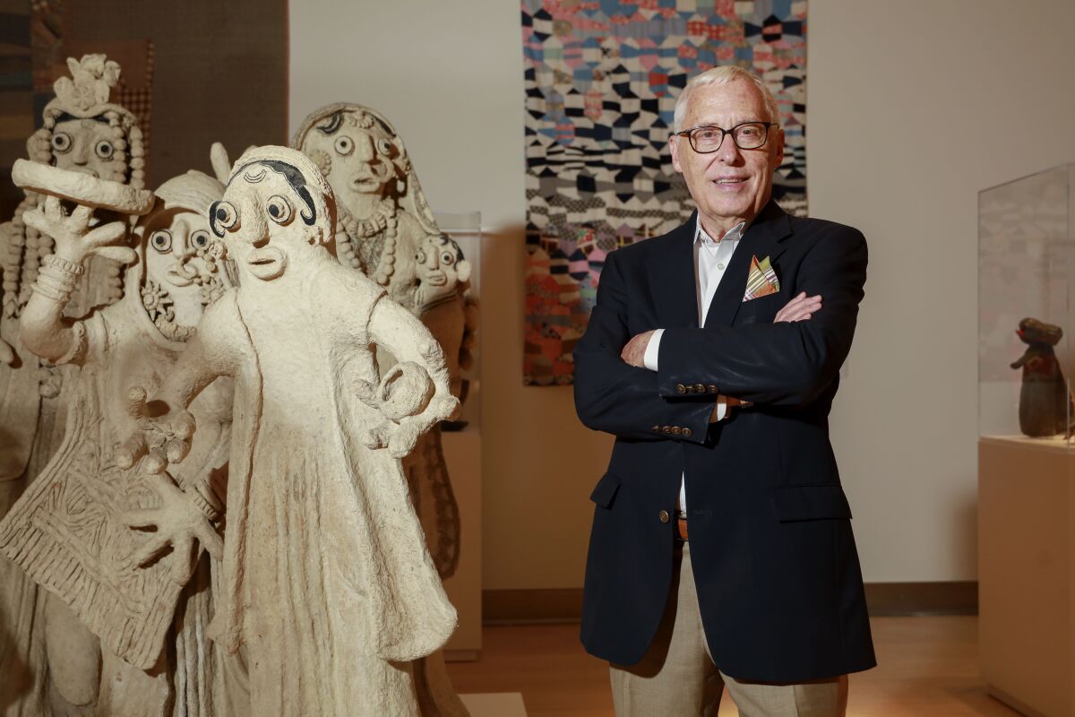 Mingei Executive Director and CEO Rob Sidner in the middle of the museum, his arms folded and standing next to a sculpture