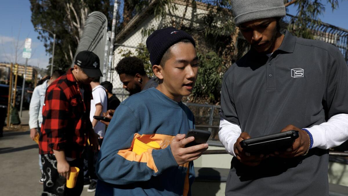 Zach Zheng, center, of Fullerton, signs up at Supreme to purchase their spring/summer collection in Los Angeles.