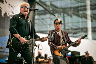 The band The Offspring performs on a stage