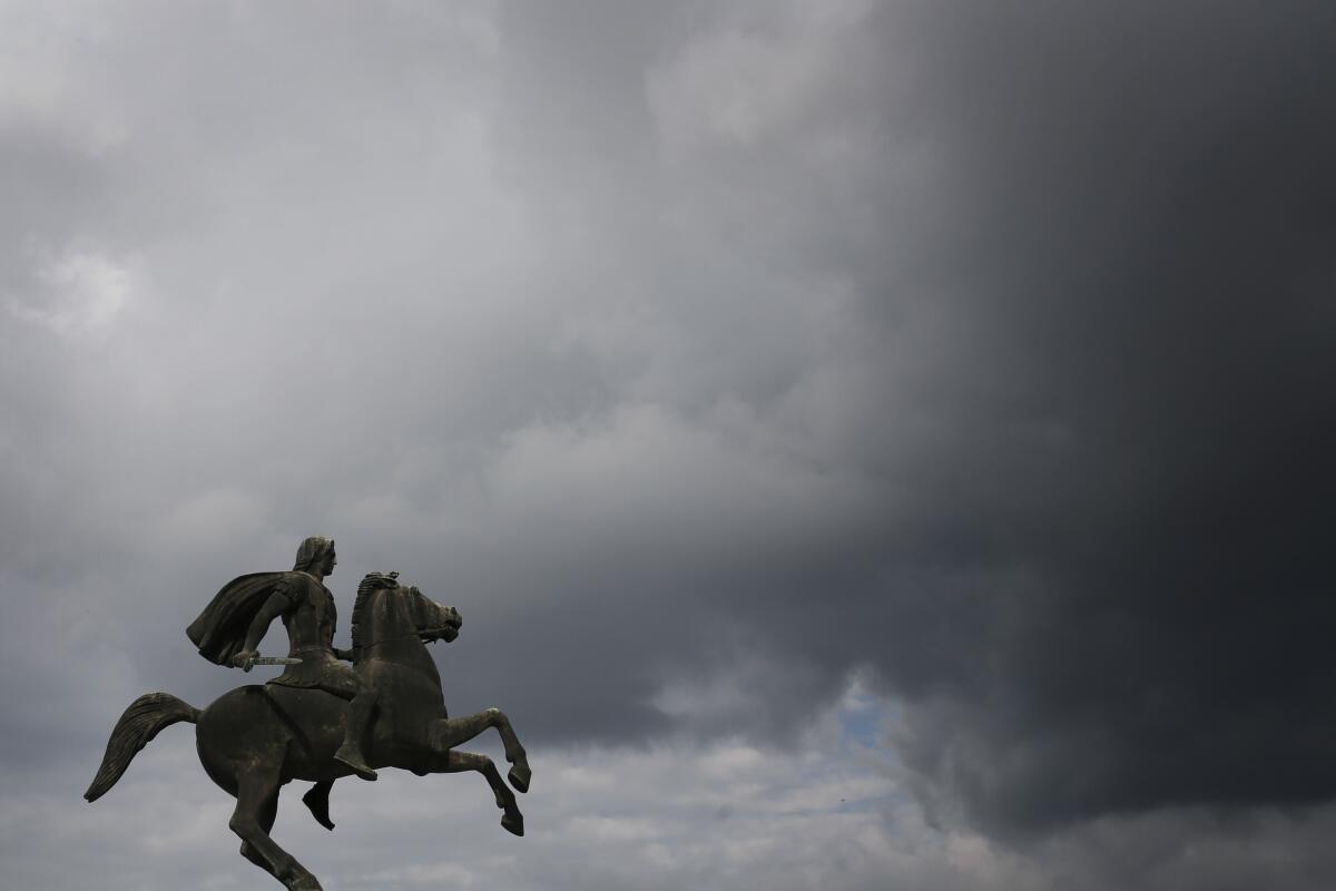 A bronze statue depicting Alexander the Great on horseback under a cloudy sky.