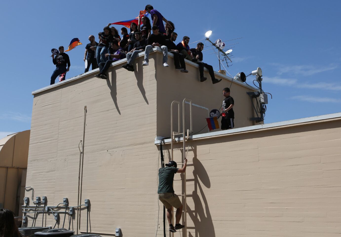 Armenian activists try to get an even higher view during a rally outside of the Turkish Consulate.