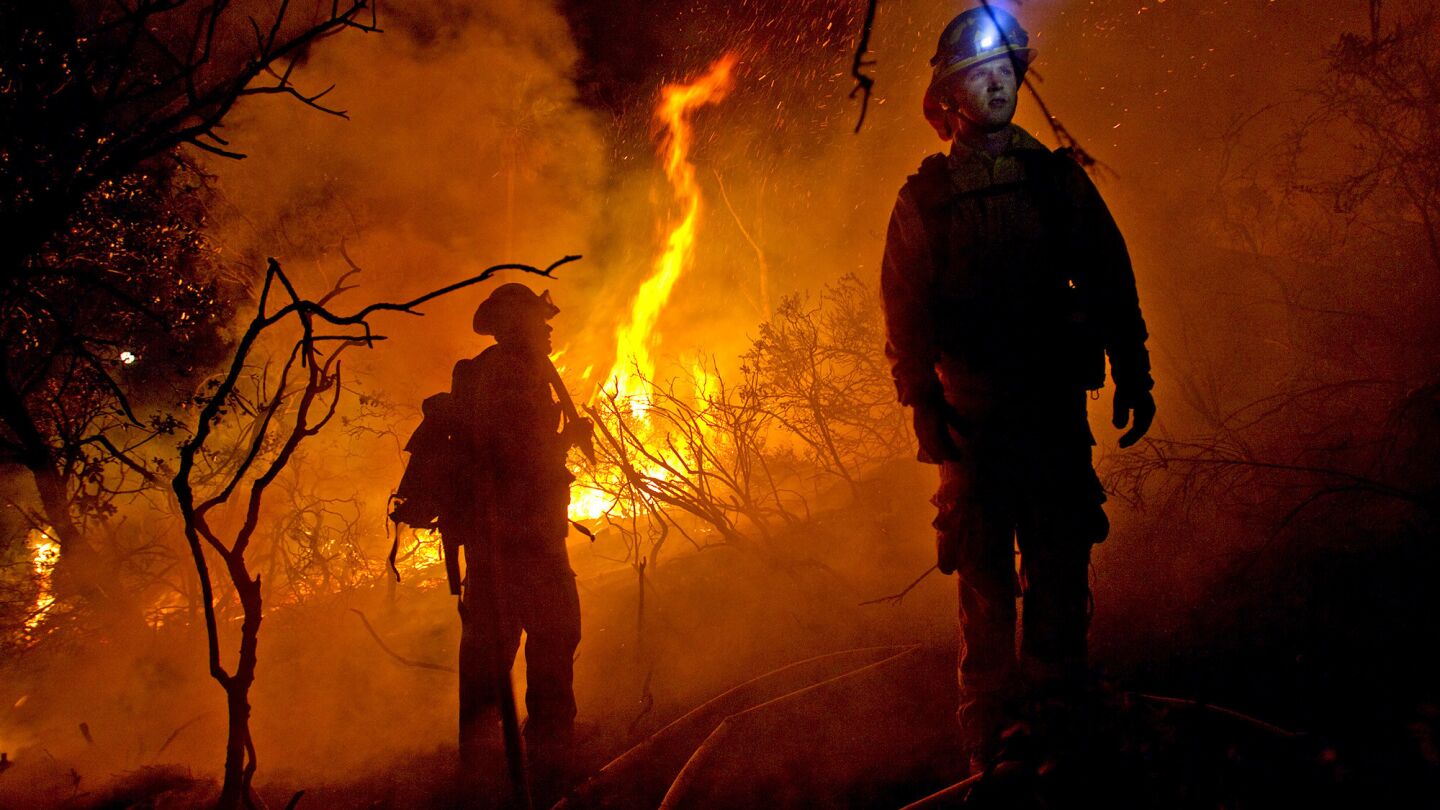 Cal Fire firefighters wait for more water as they battle a large wildfire threatening homes in the Coronado Hills neighborhood of San Marcos on Wednesday night.