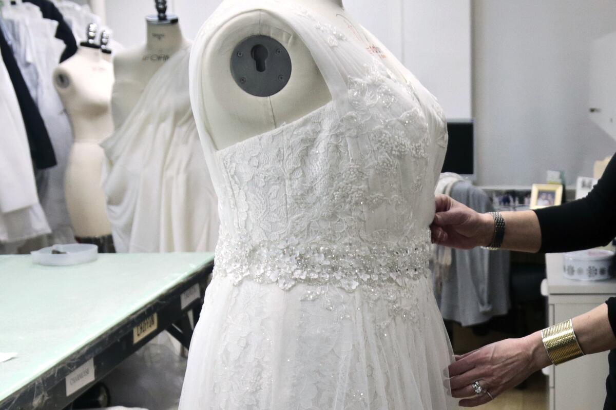 hands arrange a wedding dress on a mannequin