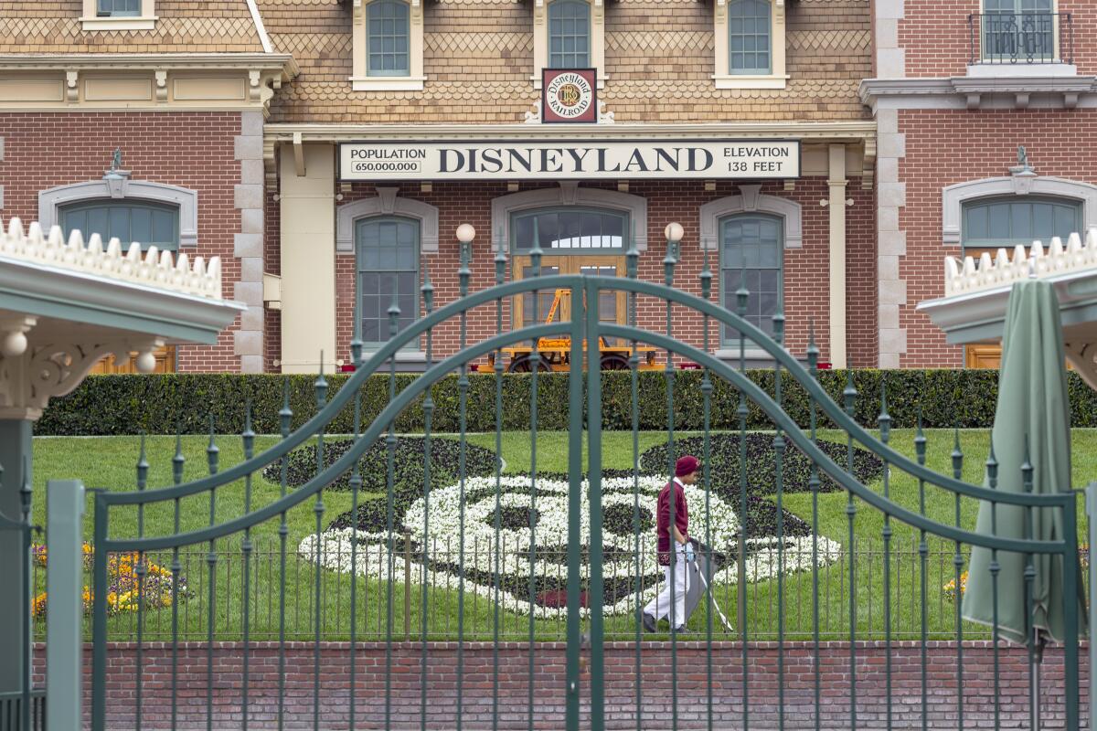 An employee cleans the grounds behind the closed gates of Disneyland on March 14, the first day of the theme park's closure.