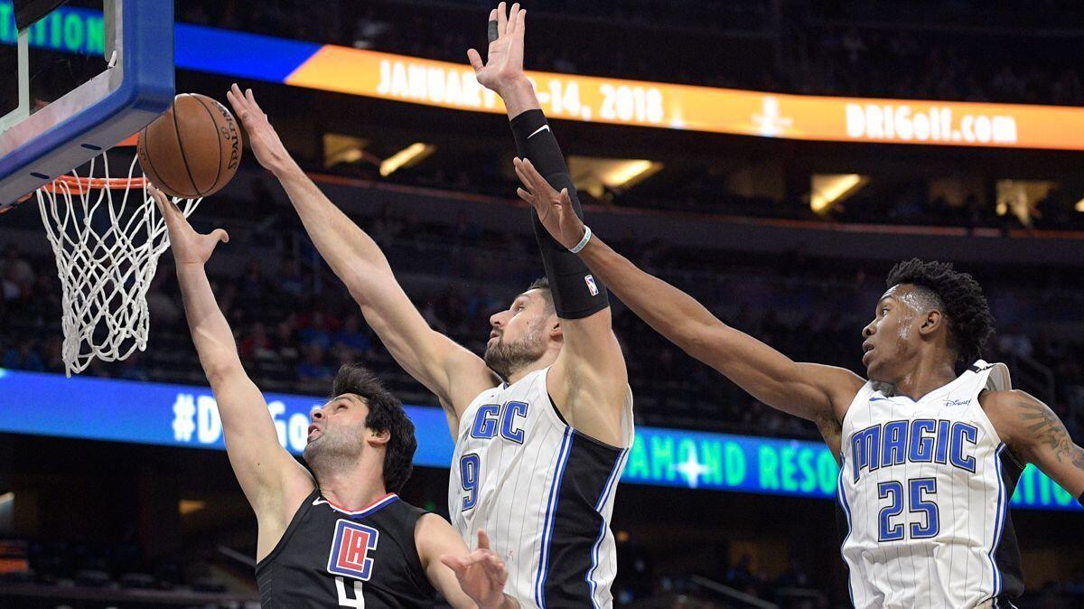 Clippers guard Milos Teodosic (4) has his shot blocked by Orlando Magic center Nikola Vucevic (9) as forward Wesley Iwundu (25) helps defend during the first half on Wednesday.