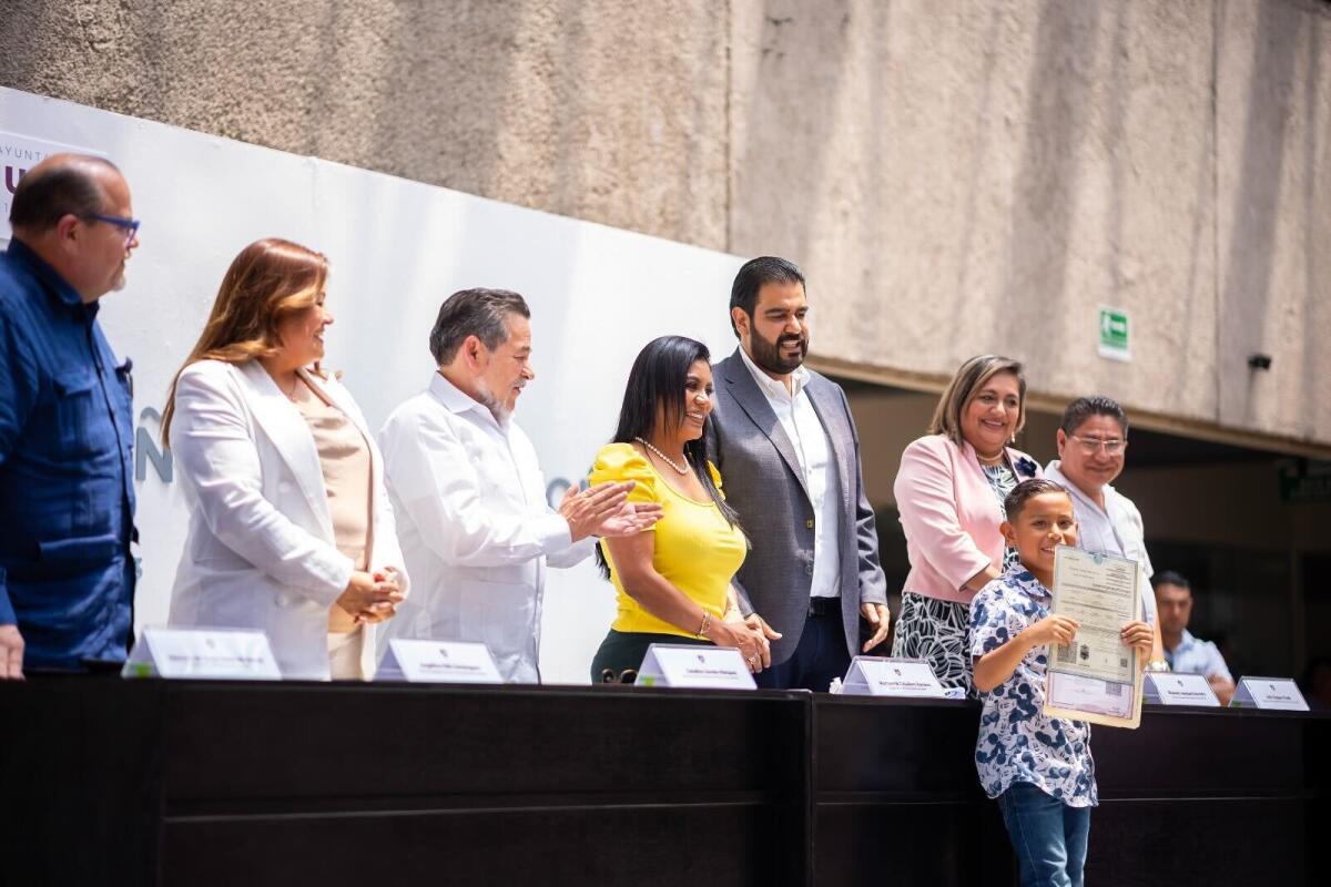 La alcaldesa de Tijuana, Montserrat Caballero (centro) entrega certificado de doble nacionalidad a Emanuel Moreno.