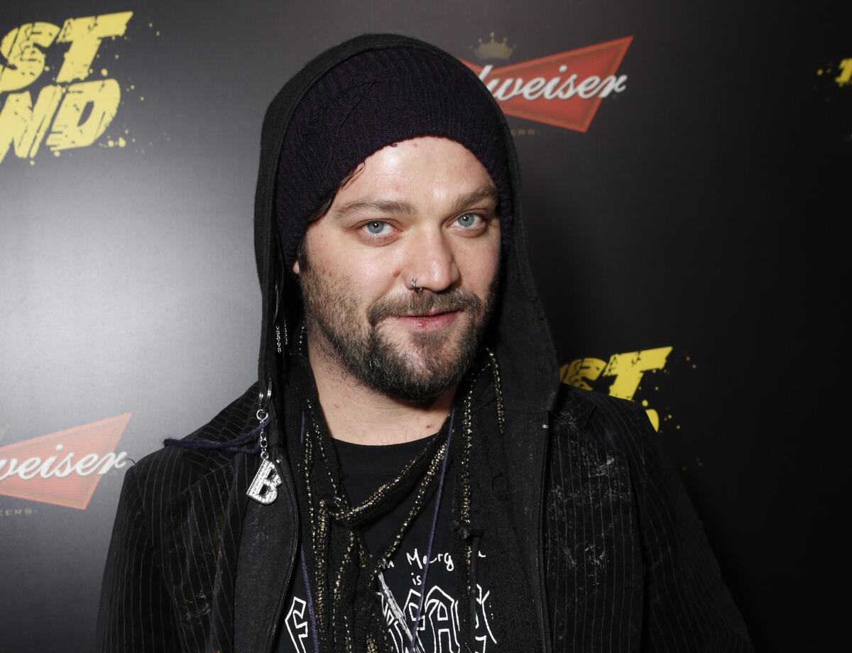 Bam Margera wearing black beanie and black hoodie, smiling with short beard