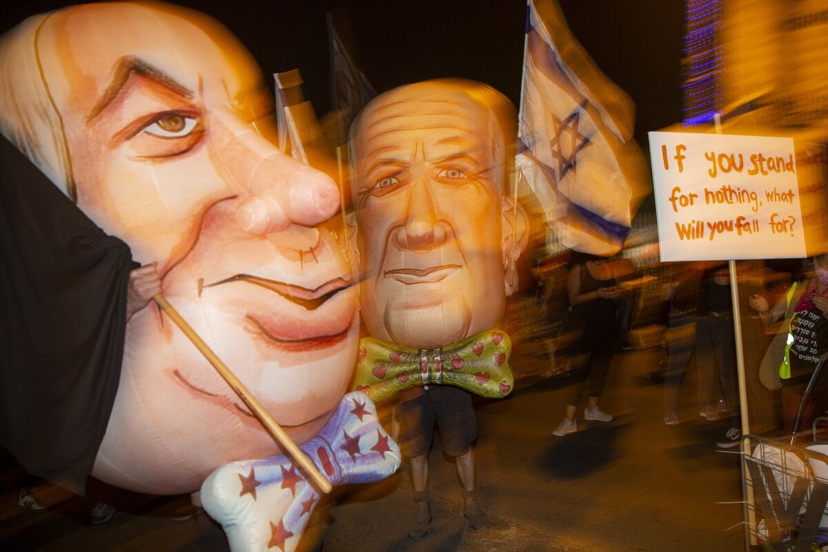Demonstrators wear mask as Israel's Prime Minister Benjamin Netanyahu, left, and Defense Minister and coalition partner Benny Gantz, right, during a protest against Israel's Prime Minister Benjamin Netanyahu outside his residence in Jerusalem, Israel, Saturday, Aug. 8, 2020. (AP Photo/Ariel Schalit)