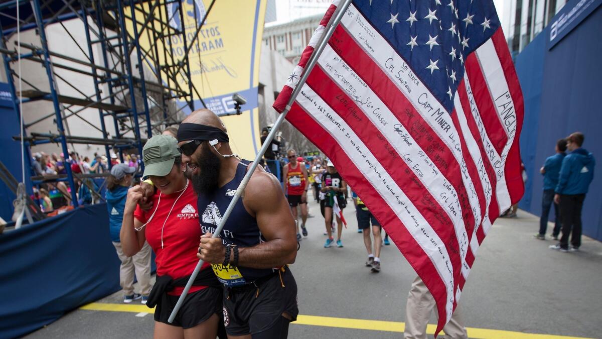 Jose Luis Sanchez is assisted after crossing the finish line at the Boston Marathon on April 17.